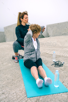Young woman exercising with senior woman stock photo NULLED
