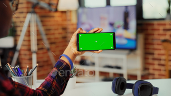 Female freelancer holding smartphone with horizontal greenscreen stock photo NULLED