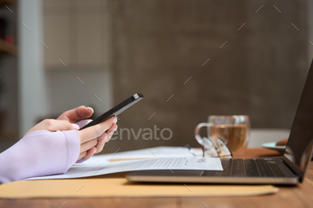 Freelancer using mobile phone and laptop indoors