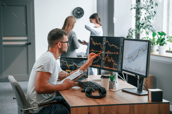 Stock broker is sitting by computer and working with exchange technology