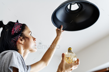 Woman changing lightbulb stock photo NULLED