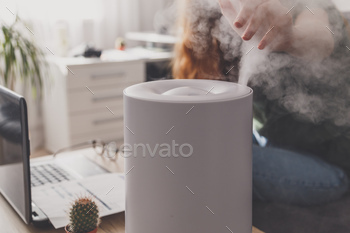 Woman freelancer uses a household humidifier in workplace