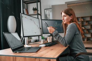 Young woman is sitting by computer and monitoring stock exchange stock photo NULLED