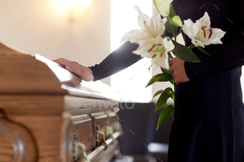 woman with lily flowers and coffin at funeral stock photo NULLED